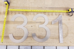 Vivid House Number | Residential House Signs | Number 331 | Brushed Aluminum Finish | Custom numbers on a wooden table with tape measure on top and beside it